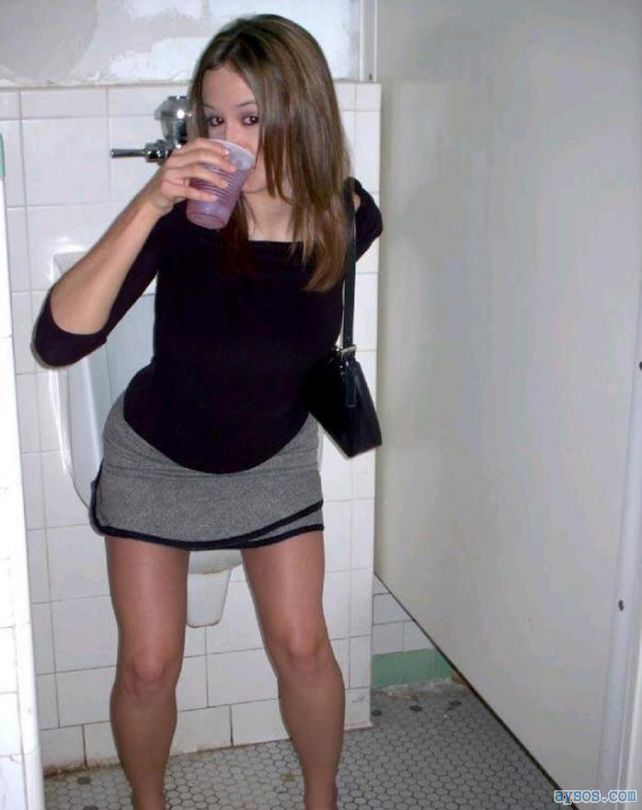 Drunk sexy party girl pulling up her short skirt in the mens room